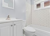 Thumbnail 12 of 15 - a bathroom with white subway tile and a white sink and toilet